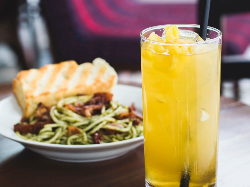 long island iced tea with black straw and chicken paste in background
