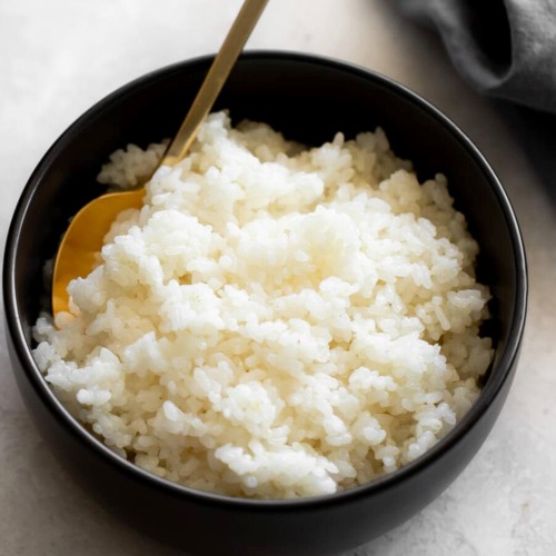 sushi rice in a black bowl on a kitchen table