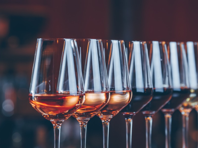 a line of wine glasses filled with samples in a tasting room