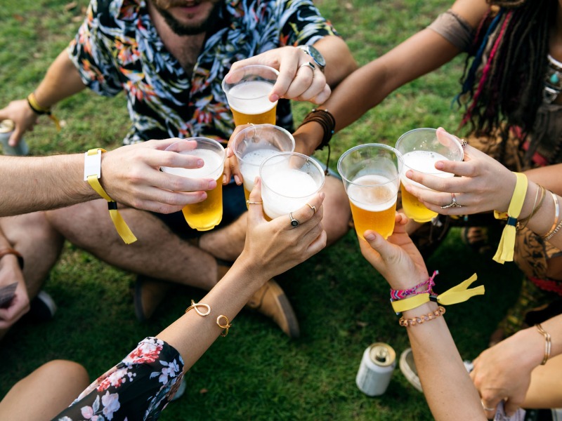 group of friends drinking beer while sitting on the grass 2022