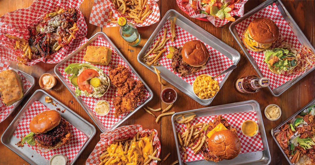 Lucy's tray of chicken dishes and sides like mac and cheese